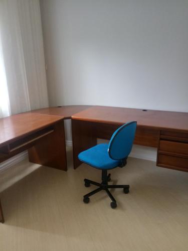 a blue chair sitting in front of a desk at Sobrado in Curitiba
