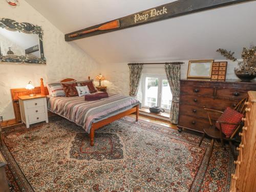a bedroom with a bed and a dresser and a window at Crow's Nest Cottage in Llanallgo