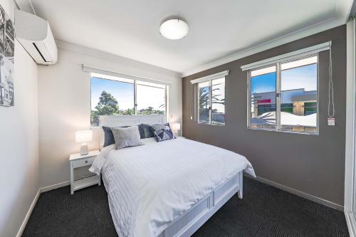 1 dormitorio con 1 cama blanca y 2 ventanas en Calamvale Business or Holiday like Home en Brisbane