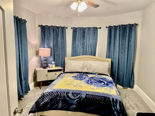 a bedroom with blue curtains and a bed and a lamp at Newly Renovated 2 Floor Apartment Getaway in Springfield