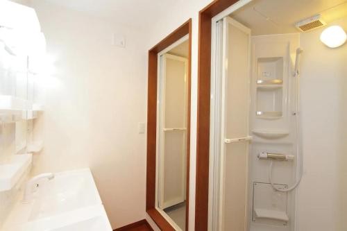 uma casa de banho com um chuveiro, um lavatório e um espelho. em Fujinokura Village C - Vacation STAY 84872 em Fujikawaguchiko
