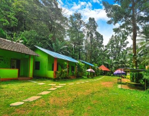 a group of houses in a yard with trees at Dandeli Eco VanaVasa by StayApart in Dandeli