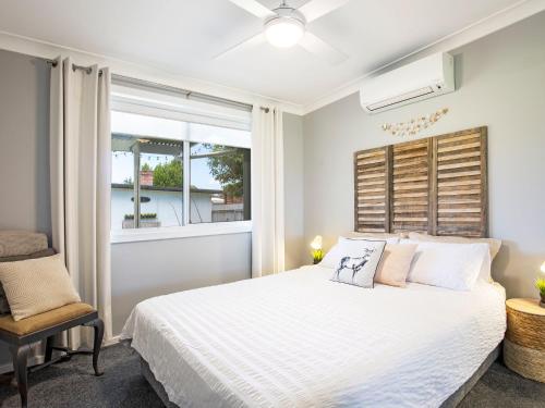 a bedroom with a white bed and a window at Roskell Retreat Pet Friendly 5 Mins Walk to Beach in Callala Beach