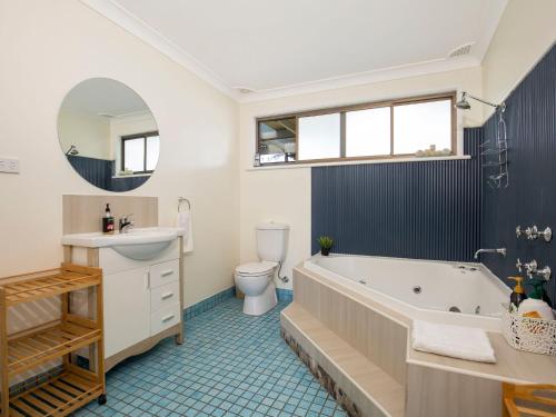 a bathroom with a tub and a toilet and a sink at Roskell Retreat Pet Friendly 5 Mins Walk to Beach in Callala Beach