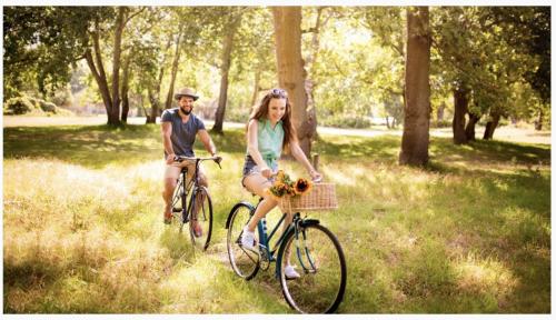 - un homme et une femme faisant du vélo dans un parc dans l'établissement Bubble Tent Hotel, à Weyregg