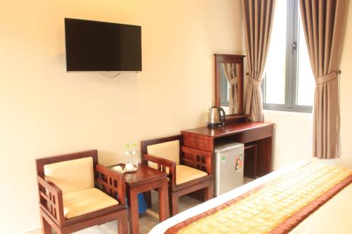 a hotel room with a television and a desk and chairs at Bonjour Da Lat Hotel in Da Lat