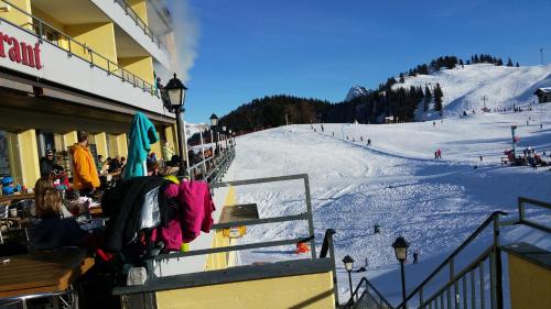 a ski resort with people sitting on a balcony and a ski slope at Elfe-Apartments Studio Apartment for 2 guests in Emmetten