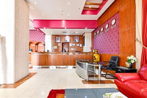 a waiting room with a red couch and a bar at OYO 118 Revira Hotel in Manama
