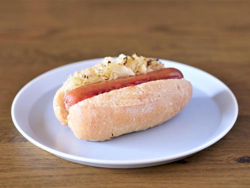 a hot dog on a white plate on a table at LAMP LIGHT BOOKS HOTEL fukuoka in Fukuoka