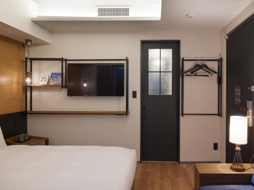a bedroom with a bed and a window and a door at LAMP LIGHT BOOKS HOTEL fukuoka in Fukuoka