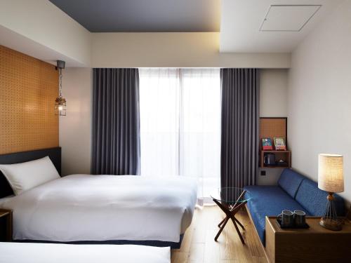 a bedroom with a white bed and a blue couch at LAMP LIGHT BOOKS HOTEL fukuoka in Fukuoka