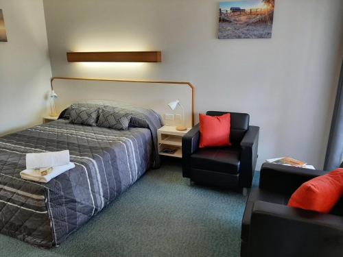 a hotel room with a bed and a chair at Country Rose Motel Warwick in Warwick