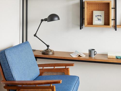 a desk with a blue chair and a lamp at LAMP LIGHT BOOKS HOTEL fukuoka in Fukuoka