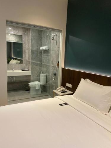 a bedroom with a bed and a bathroom with a shower at Luminor Hotel Tanjung Selor By WH in Tanjungselor