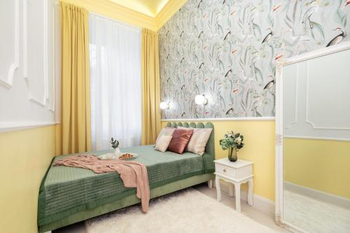 Krakow Old Town Apartments في كراكوف: غرفة نوم بسرير اخضر وورق جدران طيور