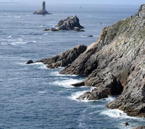 a lighthouse on a rocky coast with the ocean at Les Pierres Bleues in Saint-Coulitz