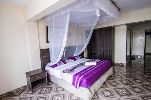 The Siron Place Hotel في Ongata Rongai : غرفة نوم بسرير مع مظلة
