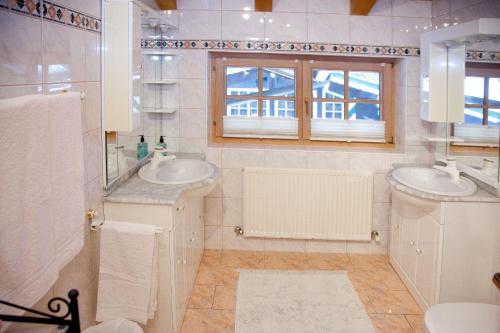 ein Bad mit 2 Waschbecken, einem WC und einem Fenster in der Unterkunft Egger Studio Hornblick in Reith bei Kitzbühel
