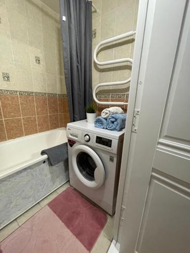 ein Badezimmer mit einer Waschmaschine und einer Badewanne in der Unterkunft Apartment on Krasina-Abay street in Öskemen