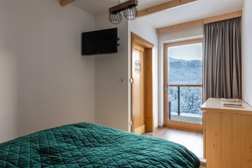 1 dormitorio con cama verde y ventana grande en Apartamenty Parzenica Zakopane en Kościelisko