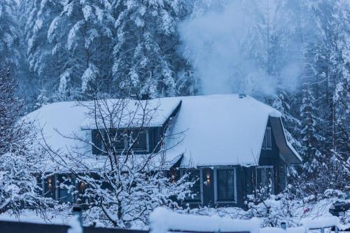 a house covered in snow with a mountain at Evita - 'Virš Ąžuolų' - Forest SPA - Horses - Lake in Paplatelė