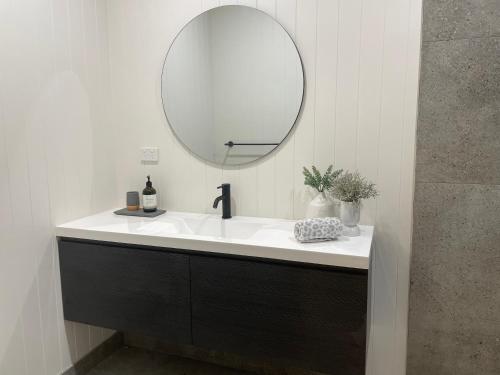 a bathroom with a white sink and a mirror at Kiama Palms on Terralong in Kiama
