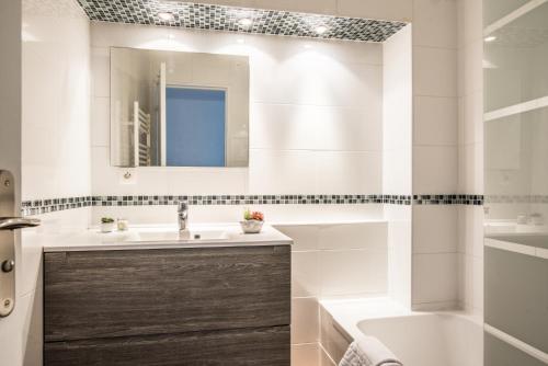 W łazience znajduje się umywalka, wanna i lustro. w obiekcie Lumineux - L'Envol - Terrasse w Strasburgu
