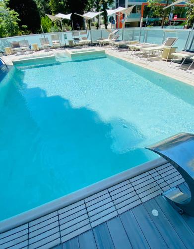 a swimming pool with blue water and lounge chairs at Aqua Hotel in Rimini