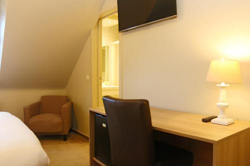 um quarto com uma secretária, uma cama e uma cadeira em Hotel Les Dunes em De Haan