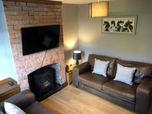 a living room with a couch and a fireplace at Moss Cottage in Willaston