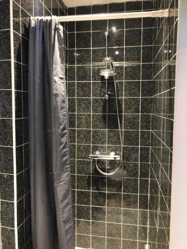 a shower with a black tiled wall at Moss Cottage in Willaston