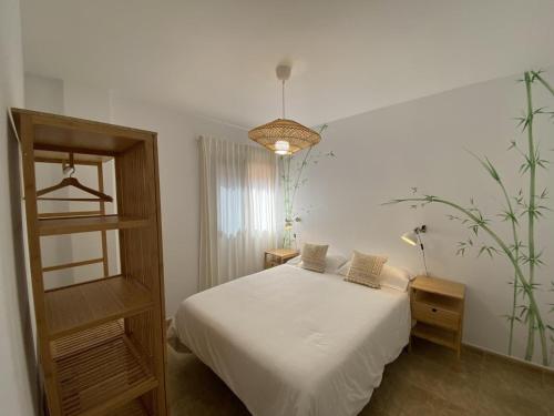 um quarto com uma cama branca e uma planta em Vivienda vacacional sur de europa b 1 3 em La Restinga