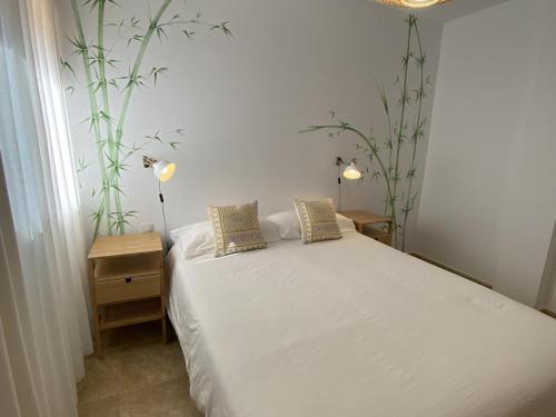 um quarto com uma cama branca e duas plantas em Vivienda vacacional sur de europa b 1 3 em La Restinga