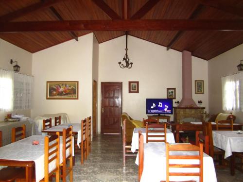 uma sala de jantar com mesas e cadeiras e uma televisão em Pousada do Alferes em Paty do Alferes