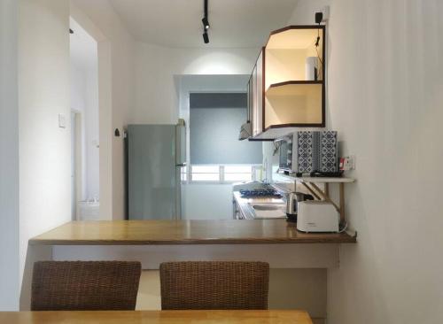 a kitchen with a counter top with two chairs at Cozy NEAR-BEACH Apartment - LazyCats' Den in Batu Ferringhi