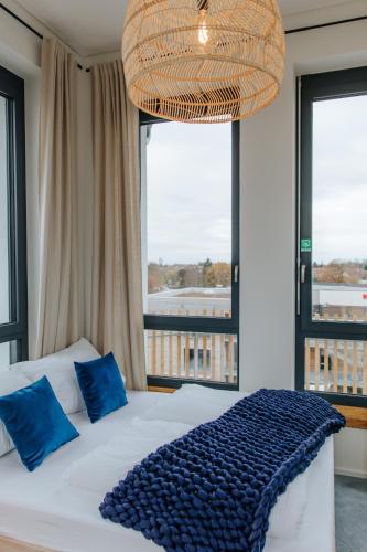 a bedroom with a bed with blue pillows and a large window at Village Turmzimmer in Kehl am Rhein