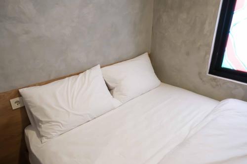 a bed with white pillows in a small room at M Cabin Karawaci in Binong