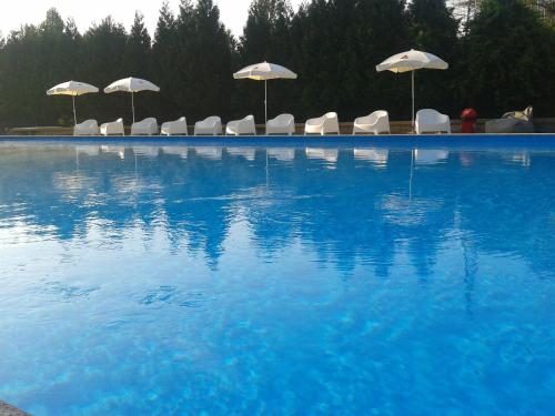 a swimming pool with white chairs and umbrellas at Hotel Vianorte in Matosinhos