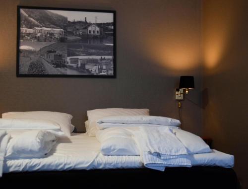 uma cama com lençóis brancos e almofadas num quarto em Rjukan hotell em Rjukan