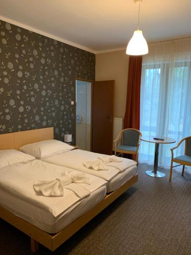 Hotel Korona في هاركاني: غرفة نوم بسرير وطاولة وكراسي
