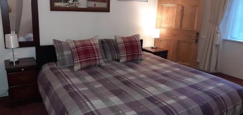 a bedroom with a bed with plaid pillows at Andreu Cottage in Callander