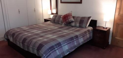 a bedroom with a bed with two night stands and two lamps at Andreu Cottage in Callander