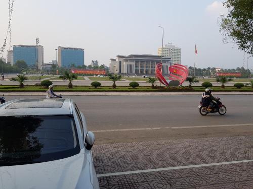 biały samochód jeżdżący ulicą z osobą na motocyklu w obiekcie Khách Sạn Hương Sơn w mieście Bắc Giang