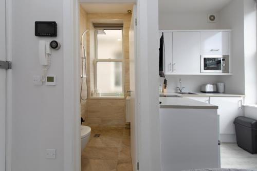 a white kitchen with a toilet and a sink at Fabulous Apartment in Superb location in London