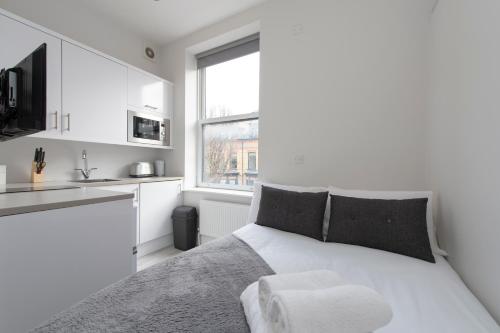a white bedroom with a bed and a kitchen at Fabulous Apartment in Superb location in London