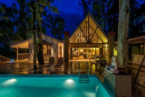 ein Haus mit Swimmingpool bei Nacht in der Unterkunft SaffronStays Tudor Rose, Panchgani - luxury chalet with beautiful valley views in Panchgani
