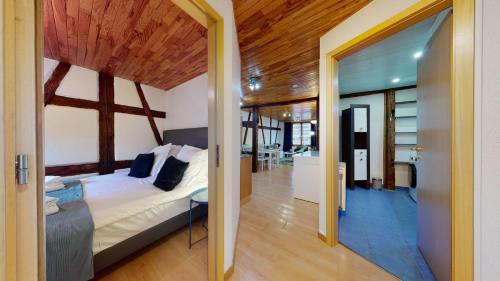 - une chambre avec un lit dans une pièce dotée d'un plafond en bois dans l'établissement Le Petit Thierenbach, à Colmar