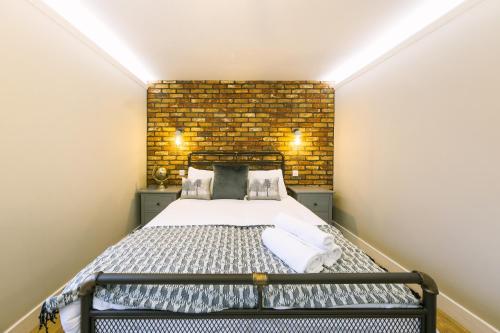 a small bedroom with a bed and a brick wall at One Bedroom Apartments in Gloucester road north in Bristol