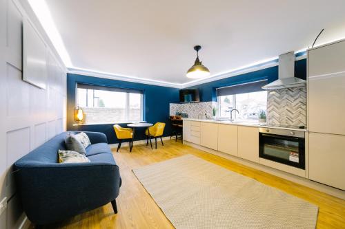 a living room with a blue couch and a kitchen at One Bedroom Apartments in Gloucester road north in Bristol