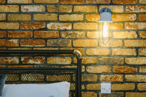 a light on a brick wall next to a bed at One Bedroom Apartments in Gloucester road north in Bristol